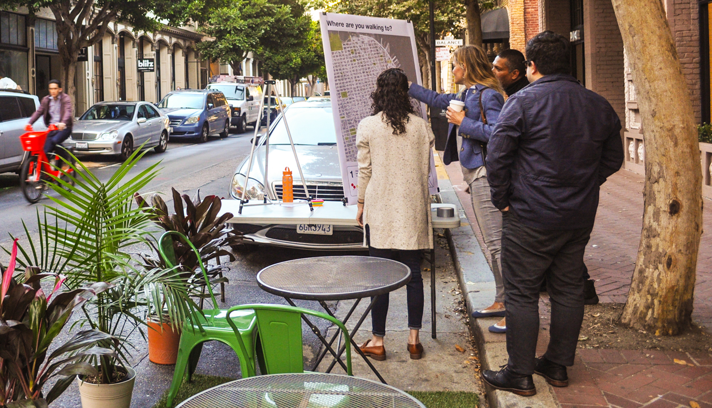 Page Planner Annie Ryan, standing in the San Francisco parking space and facing the map, talks to passers-by about where they're walking that day. - Page